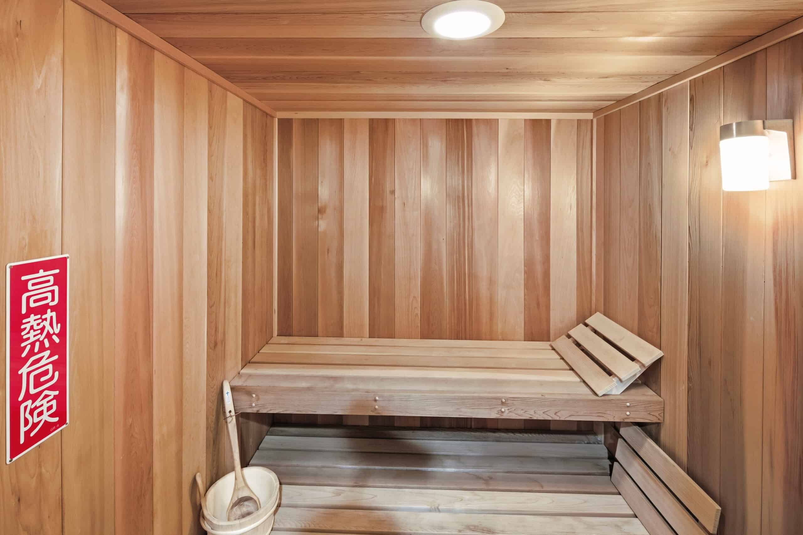A sauna room with wooden interior and a warning sign in Japanese.