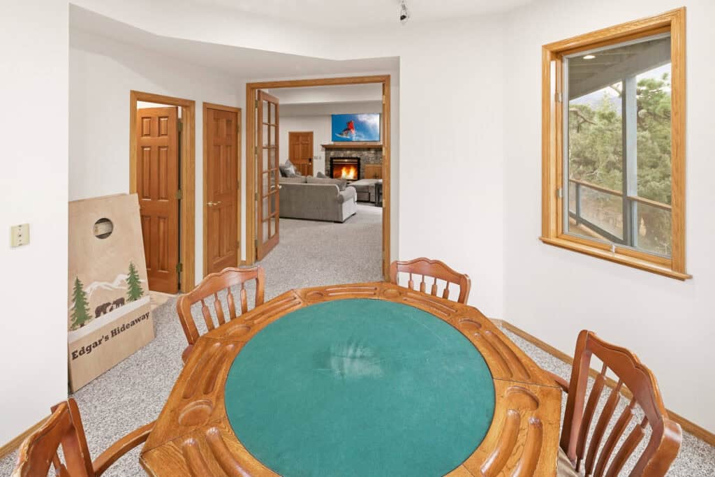 Dining area with wooden table and view into living room with fireplace.