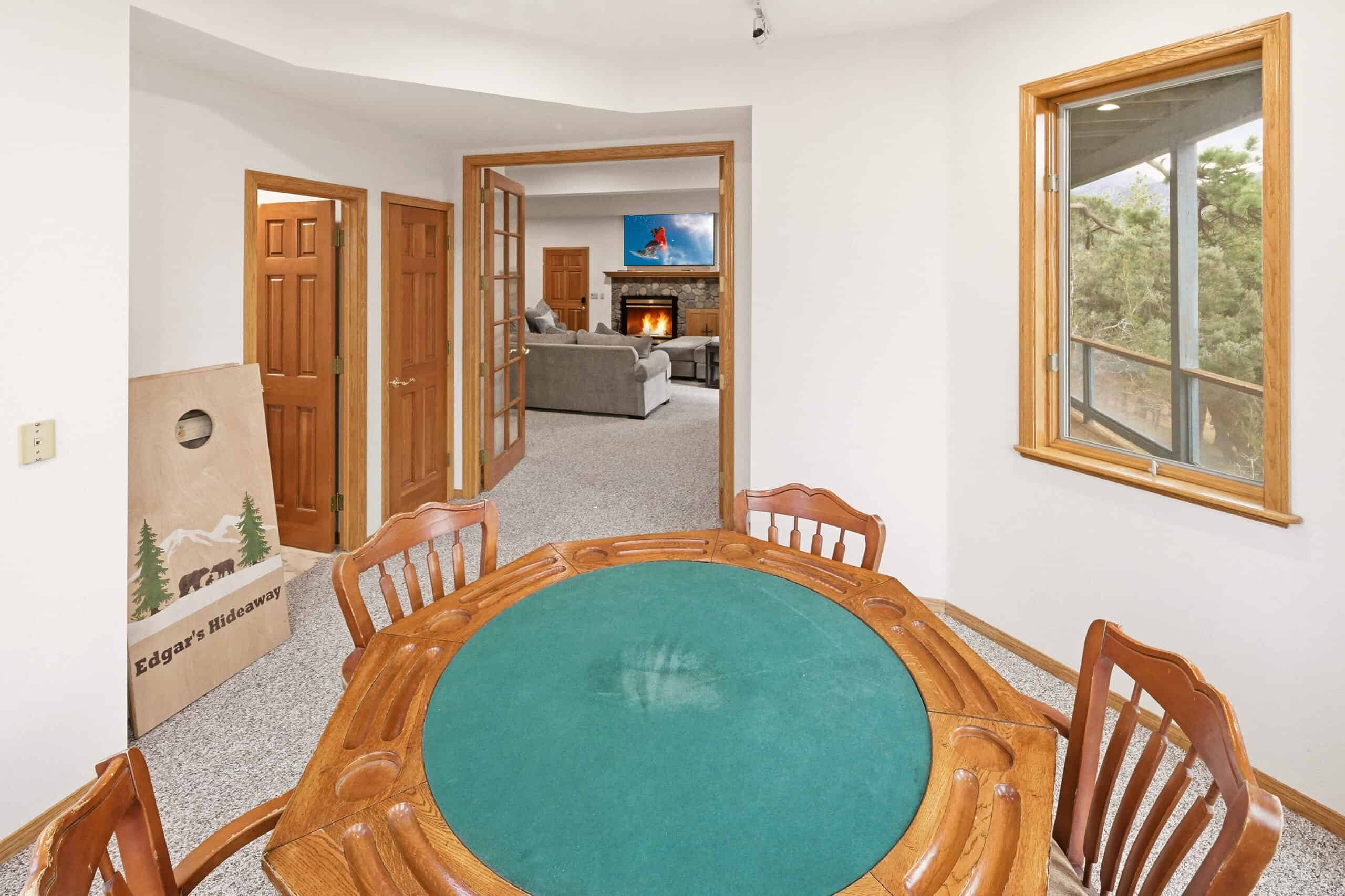 Dining area with wooden table and view into living room with fireplace.