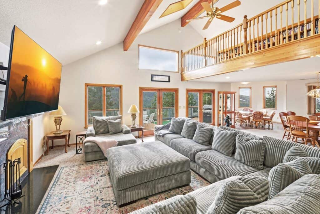 Bright living room with high vaulted ceilings and large windows offering natural light. Cozy seating.