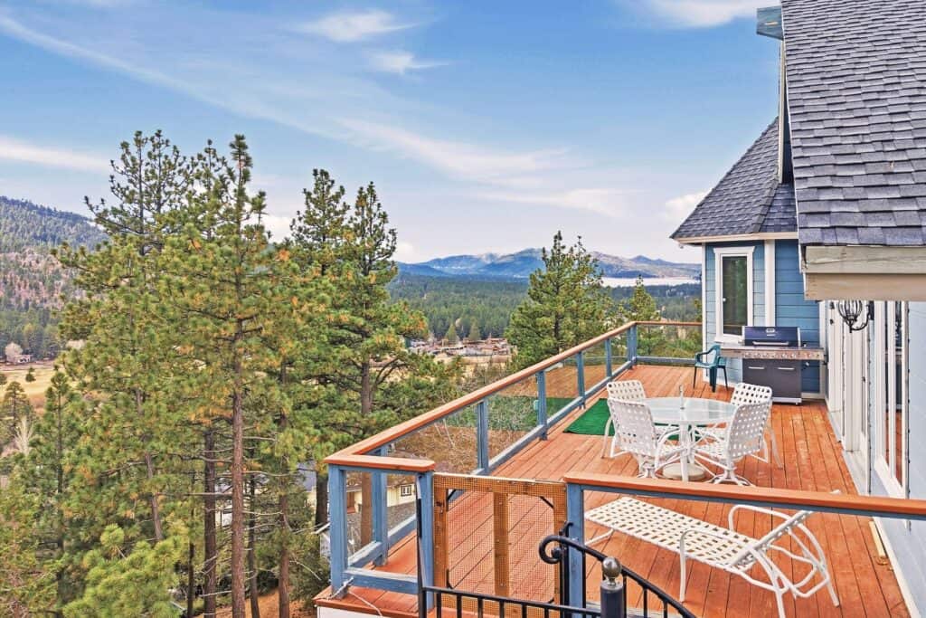 Balcony with outdoor furniture overlooking a forested mountain landscape.