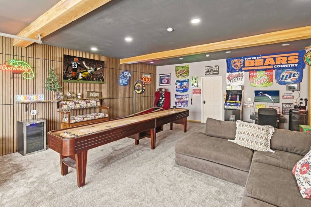 Recreational game room with shuffleboard, arcade games, and sports memorabilia decor.