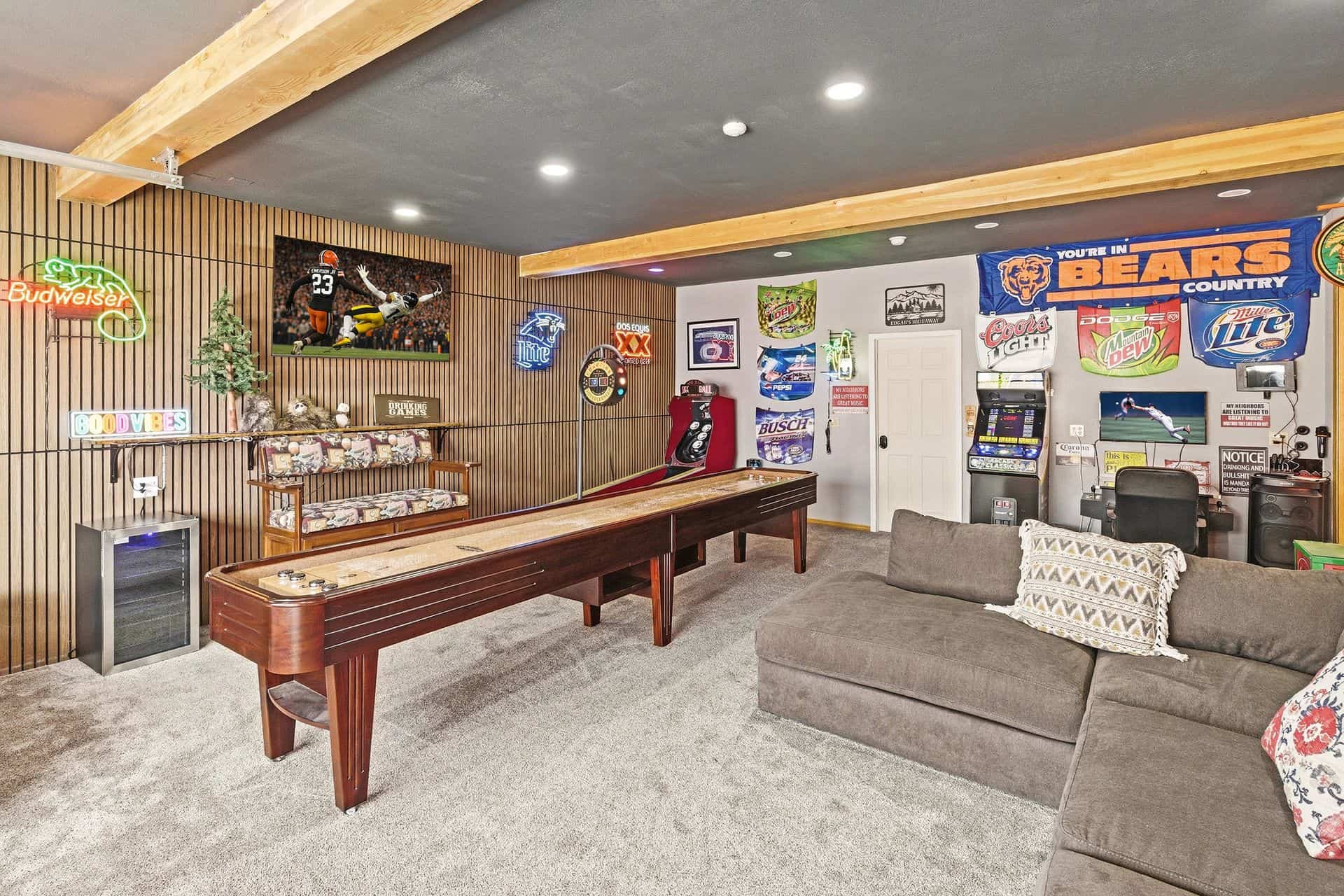 Recreational game room with shuffleboard, arcade games, and sports memorabilia decor.